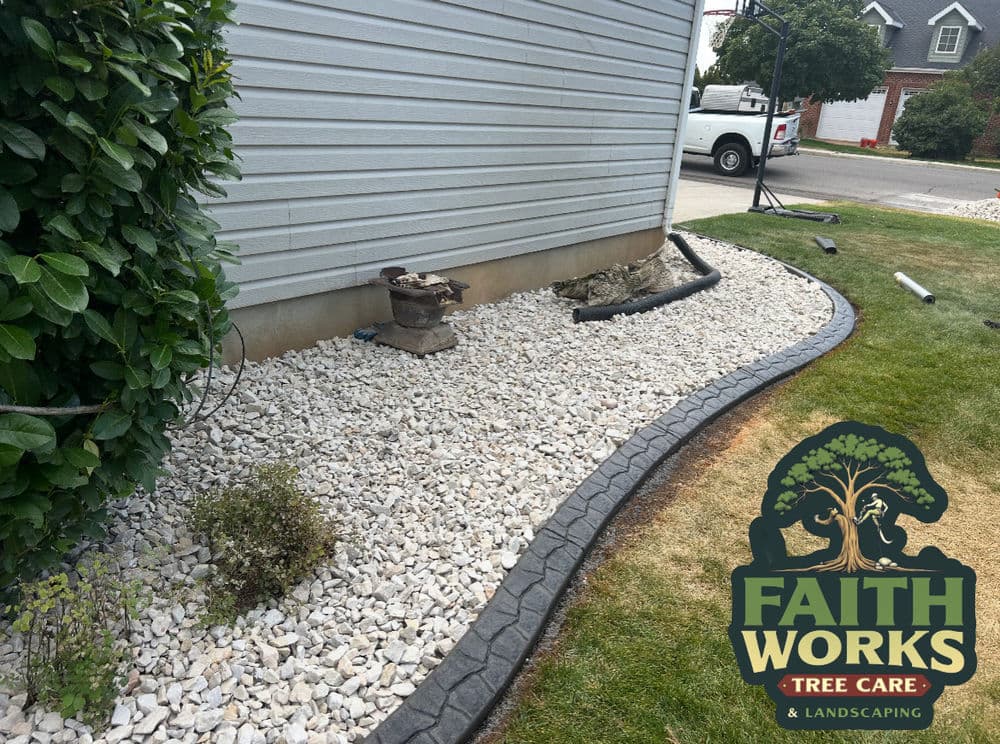 Landscaped area with gravel and edging, featuring Faith Works Tree Care logo.