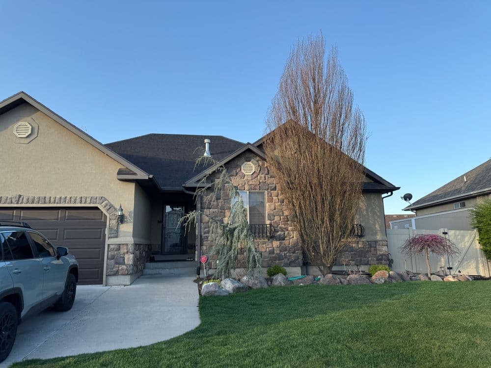 Modern home with stone exterior, well-maintained lawn, and clear blue sky in the background.