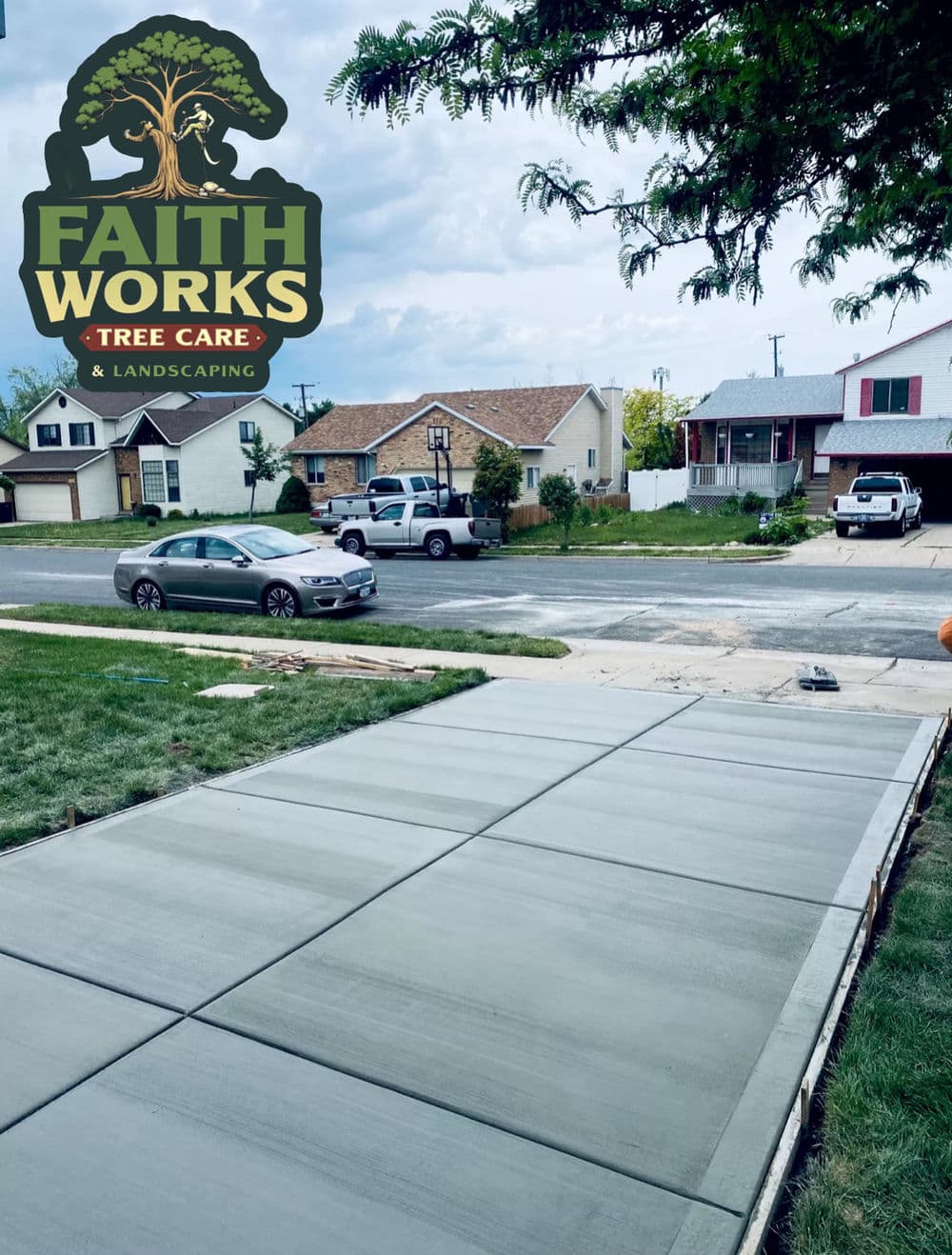 Newly paved concrete driveway in residential neighborhood with tree care logo.