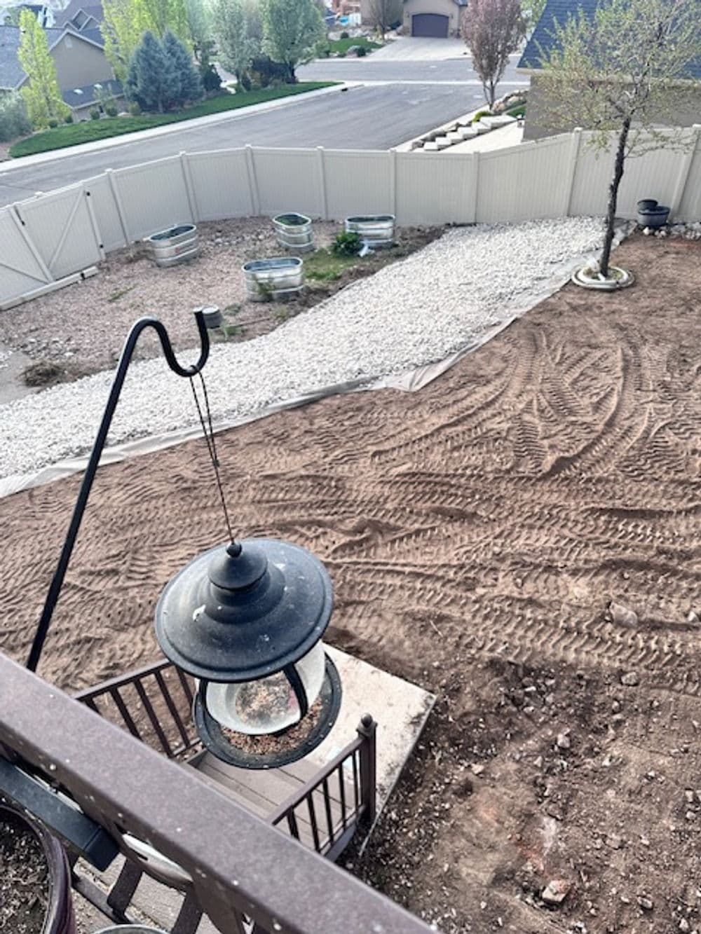 View of a landscaped yard with gravel, planters, and a hanging lantern.